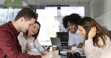 Equipe em sala de reunião revisando metas e critérios de bonificação por resultados, com laptop, documentos e anotações sobre a mesa.