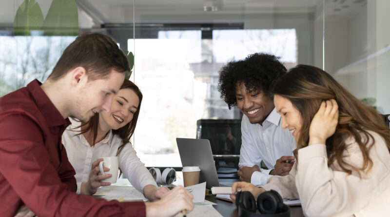 Equipe em sala de reunião revisando metas e critérios de bonificação por resultados, com laptop, documentos e anotações sobre a mesa.